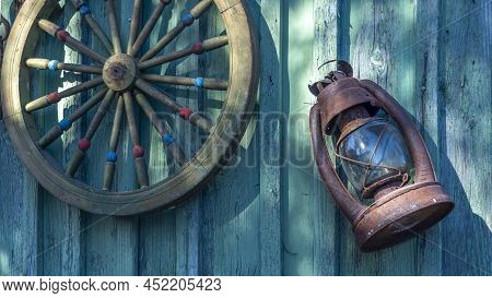 Betty Lamp And Spinning Wheel In The Background Of The Old Log-house Wall With Sign Nomber One. Rura