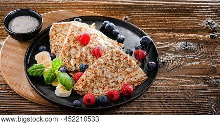 A Plate Of Pancakes With Cheese And Fruits