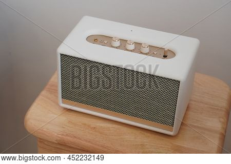 Beautiful White And Black, Gold Rectangular Loudspeaker On Wooden Chair, White Wall Background, Tech
