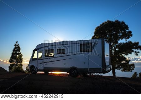 Camper Van Parked Against Sunset Light And Trees. Concept Of Alternative Lifestyle Vanlife And Trave