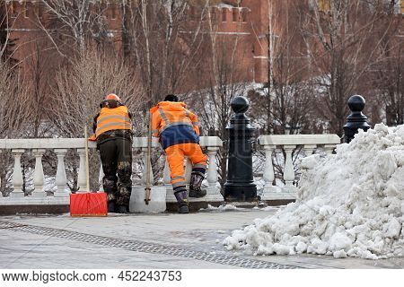 Two Workers With Shovels Standing On Park Trees  Background. Janitors During Rest, Street Cleaning A
