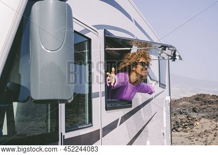 Cheerful Adult Woman Open Arms Outstretching Outside The Window Of Her Modern Van Camper Admiring An