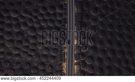 Long Straight Asphalt Road In The Middle Of Black Sand Volcanic Vineyard. Concept Of Transport Vehic