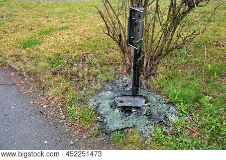 Vandals Set Fire To A Plastic Trash Can In The Park. Molten Green Mass On The Cracked Under The Post