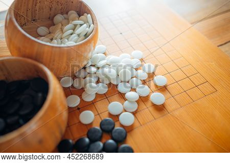 A Set Of Go Or Igo Game Stones In The Wooden Bowls On The Grid Table.