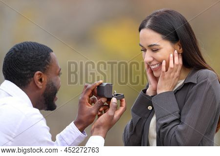 Interracial Couple Proposing Marriage Standing In A Park