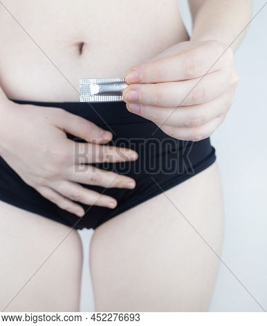 Vaginal Or Rectal Candle In The Hands Of A Woman Against The Background Of The Abdomen And Underwear