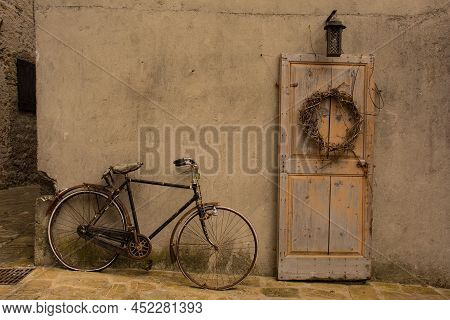 An Old Wooden Door And Bike In Poffabro, An Historic Medieval Village In The Val Colvera Valley In P