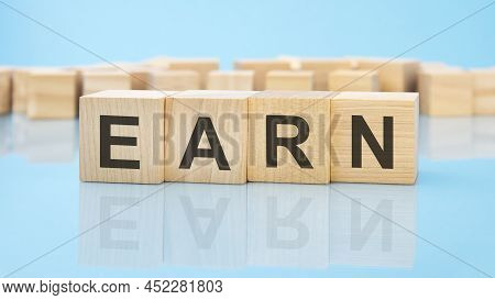 Letters Earn Made With Wood Building Blocks. Blue Background. Business Concept