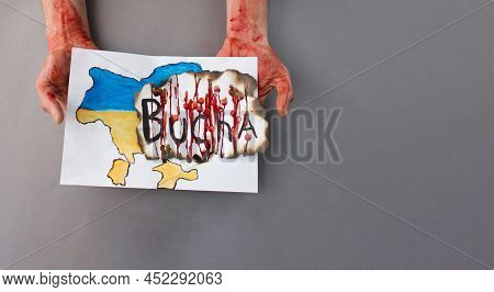 Men's Hands In Blood Hold A Map Of Ukraine With The Inscription Of The City Of Bucha. Killings Of Ci