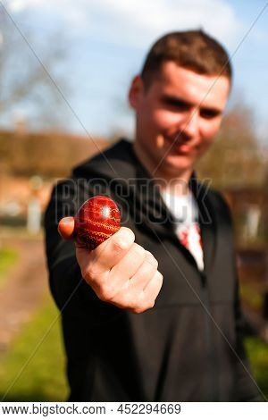 Defocus Ukrainian Young Man Holding One Colored Red Egg On Nature Background. Easter, Ukraine. Craft