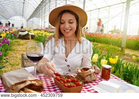 Beautiful Young Woman Having Picnic. Girl Takes A Strawberry. Fresh Harvest In Coutryside On Spring 