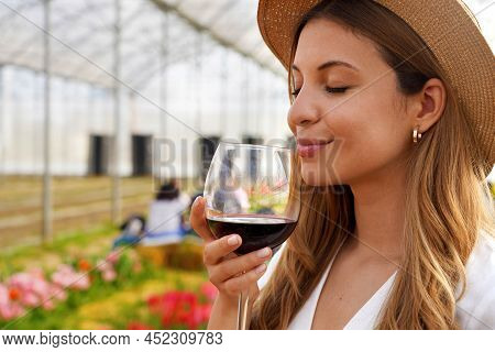 Close-up Of Beautiful Woman Smelling Red Wine From Glass With Closed Eyes