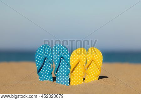 Multicolor Flip-flops On The Sandy Baech Against Sea And Sky