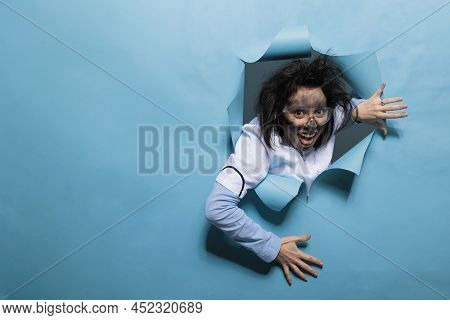 Foolish Humorous Scientist With Comic Expression On Blue Background. Young Adult Chemist With Wacky 