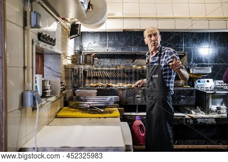 Faro, Portugal - March 11, 2022: Experienced Man Grilling The Best Chicken In The City In Churrasque