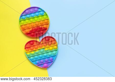 Popular Silicone Multi-colored Anti-stress Toy Pop It In The Shape Of Heart On Yellow Blue Backgroun