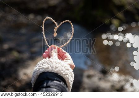 A Heart Shape Of Cord Is Held By A Human Hand In Front Of A Place Of Nature. Reconnect To Natural Ma
