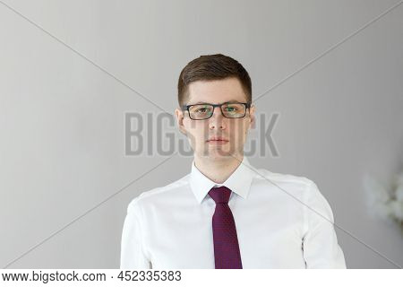 Portrait Of A Businessman. Office Worker In A White Shirt And Tie Looking At The Camera