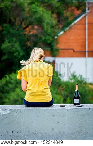 Back View Of Beautiful Blonde Girl. Near With Her Bottle Of Alcohol And Pack Of Cigarette Hair In Mo