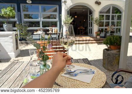 Woman Relaxing With A Glass Of White Wine In A Garden Of Restaurant