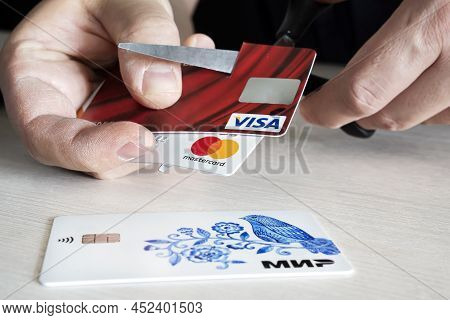 April 2, 2022. Barnaul. Russia: A Man Cuts Bank Credit Cards Of The Type And Mastercard With Scissor