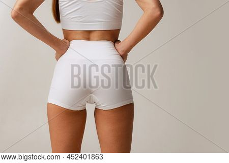 Sportive Bottocks, Legs. Cropped Image Of Female Body In White Uderwear Isolated Over Gray Studio Ba