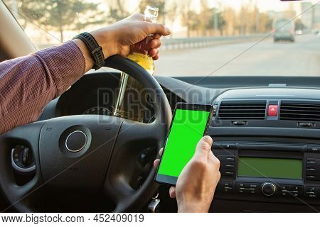 Man Drinking Alcohol While Driving In His Car And Looks In Smartphone.