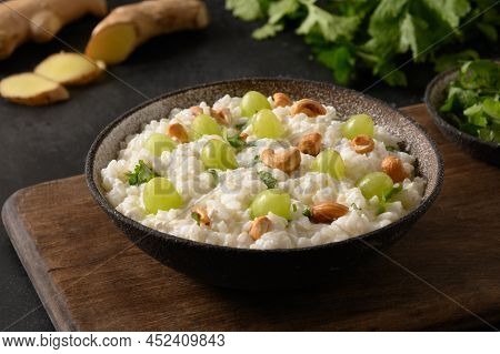 Curd Rice With Cashews, Grapes, Cilantro, Ginger On A Black Background. Indian Cuisine