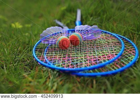 Bandbinton Rackets And Shuttlecock Lie On A Green Lawn