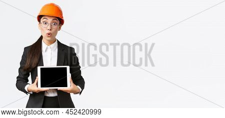 Impressed Asian Female Construction Engineer, Businesswoman In Safety Helmet And Suit Showing Chart,