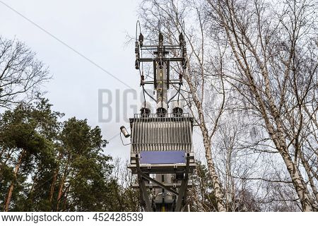 Low Voltage Transformer Station Standing On A Concrete Pole At The Edge Of The Forest.