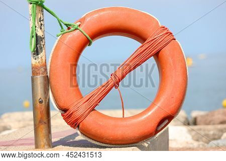 Plastic Orange Lifebuoy On The Rocks Is A Tool For The Protection Of Swimmers