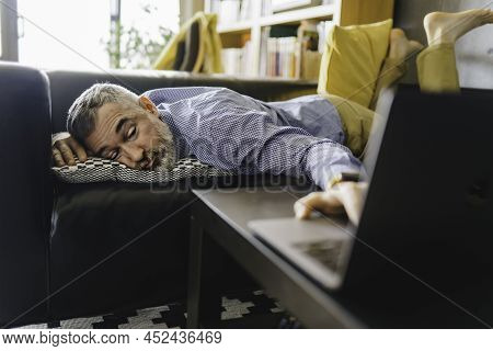 Mature Man Feeling Stress And Tired Of The Computer Lay On The Couch With A Laptop In Front