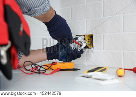 Electrician With Screwdriver Repairing Power Socket Indoors, Closeup