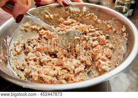 Chef Stirs Salmon Dish In Bowl With Spoon
