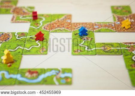 Petrozavodsk, Russia, April 2022: Carcassonne Board Game, Game Cards And Colored Chips On Wooden Tab