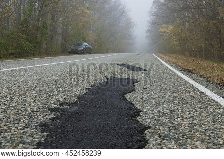 Fresh Patches After Patching The Road. A Country Road In A Foggy Forest. There Is A Car Standing On 