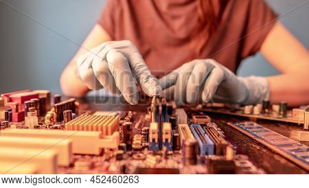 The Engineer's Gloved Hand Holds The Computer's Ram Chip Against The Background Of The Motherboard. 