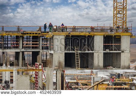 Monolithic Frame Construction Of The Building. Workers Working At The Construction Site At Home. The