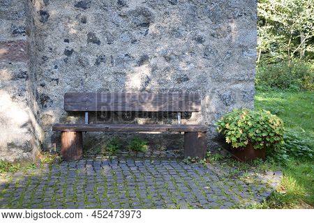 Wooden Park Bench At A Medieval Wall