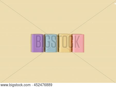 Four Rubber Erasers In Pastel Colors On A Light Yellow Background. National Rubber Eraser Day Concep