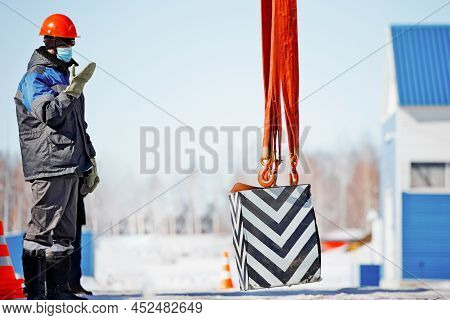 Slinger In Helmet Works Outside. Signal To Lift Load Up. Long Workflow. Work Of Slinger In Winter In