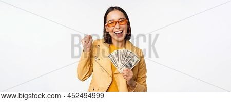 Microcredit And Money Concept. Stylish Asian Young Woman In Sunglasses, Laughing Happy, Holding Doll