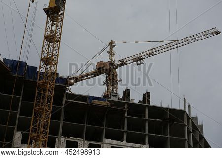 Construction Yellow Crane Builds A Tall Multi-apartment Residential Building From White Bricks And C