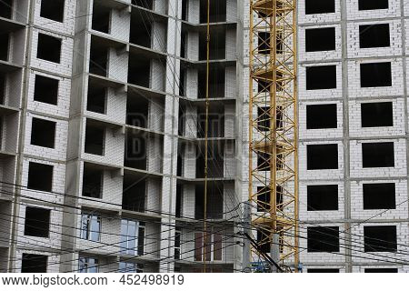 Construction Yellow Crane Builds A Tall Multi-apartment Residential Building From White Bricks And C