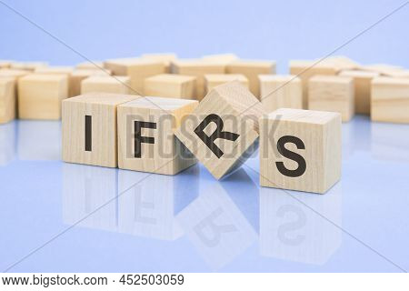 Wooden Cubes With The Letters Ifrs On The Bright Surface Of A Pale Lilac Table. Ifrs - Short For Int