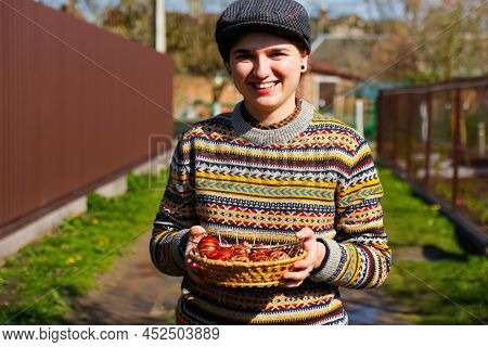 Defocus Ukrainian Young Smiling Woman In Hat Holding Plate Of Collection Of Red Egg On Nature Backgr