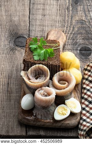 Homemade  Marinated Herring Roll With Rye Bread And Baby Potato With Quial Eggs On Wooden Table
