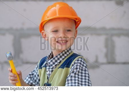 Kid In Hard Hat Holding Hammer. Happy Smiling Little Child Helping With Toy Tools On Construciton Si